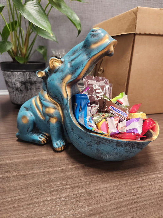 Blue hippo-shaped candy dish filled with colorful candies on a wooden surface.