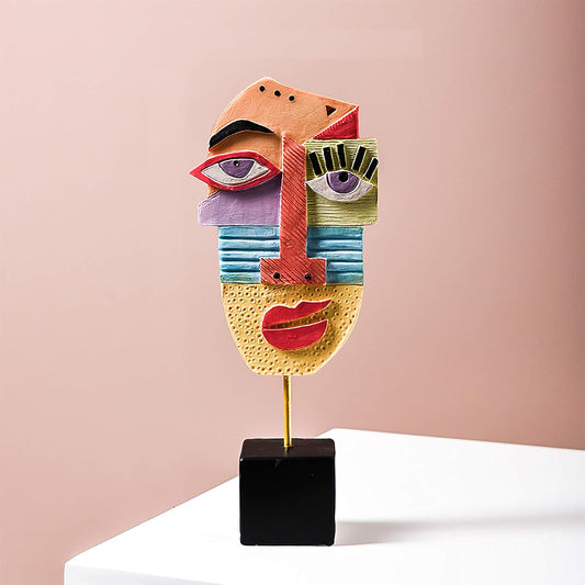 Colorful abstract face sculpture on a stand against a pink background