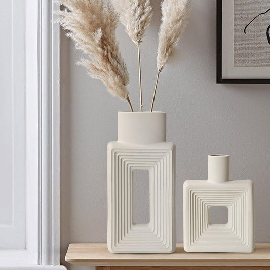 Two decorative vases with textured design on a wooden surface against a gray wall.