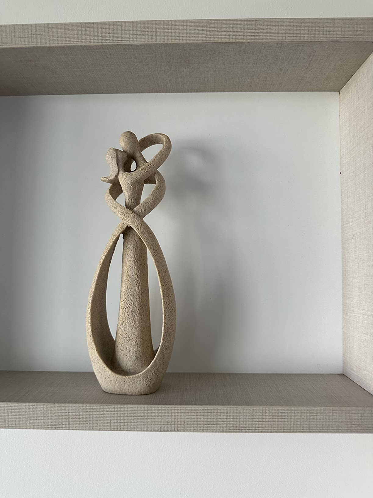 Abstract stone sculpture on a shelf against a plain wall