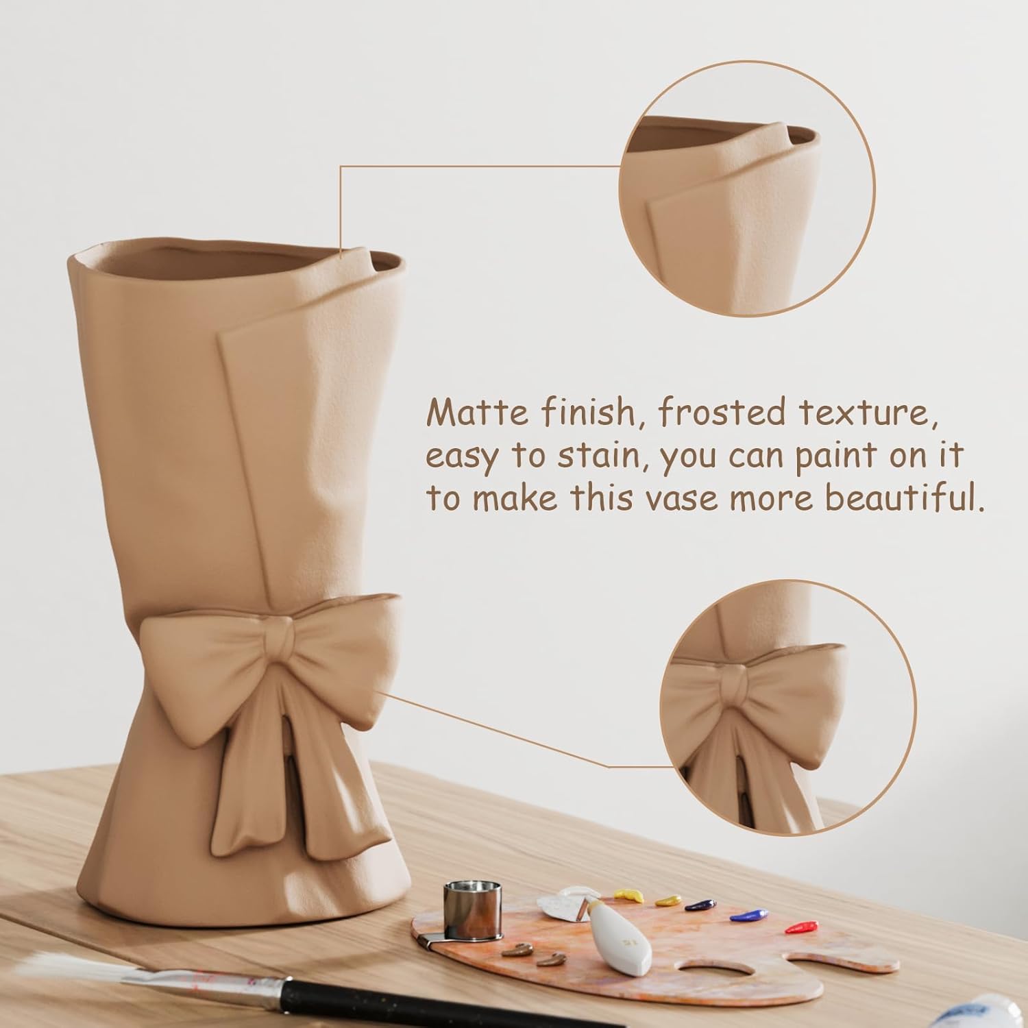 Beige vase with bow design on a wooden surface with painting tools, on a light beige background.