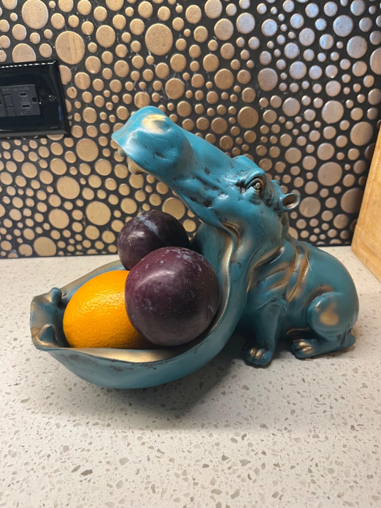 Blue hippo-shaped fruit bowl with fruits on a countertop