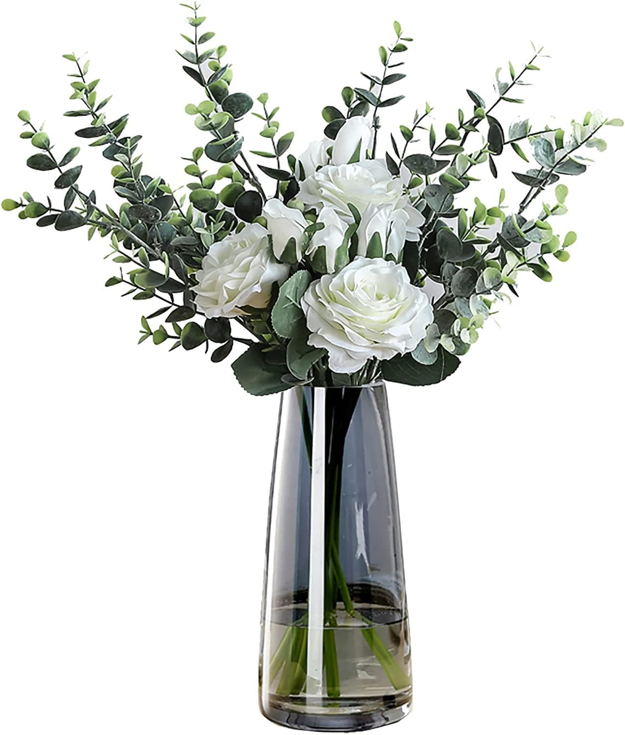 Clear glass vase with white flowers and green leaves on a white background