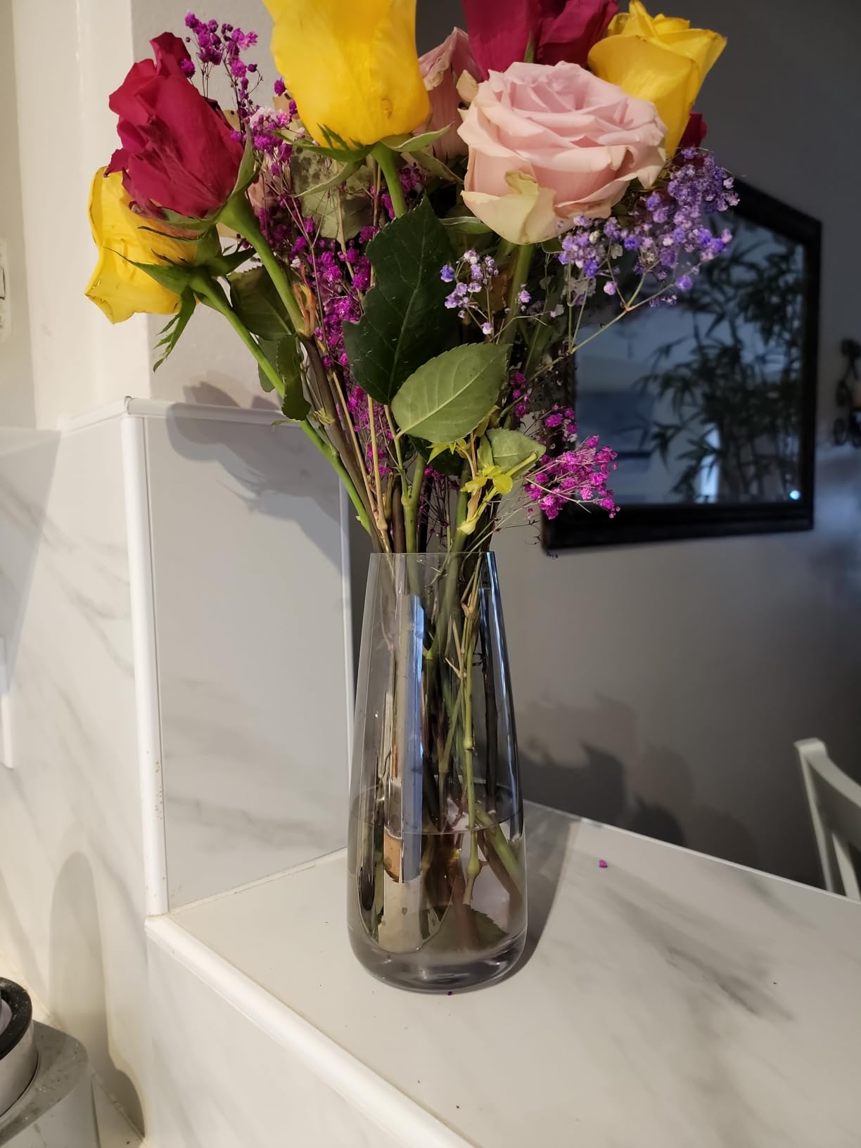 Clear vase with colorful flowers on a white surface