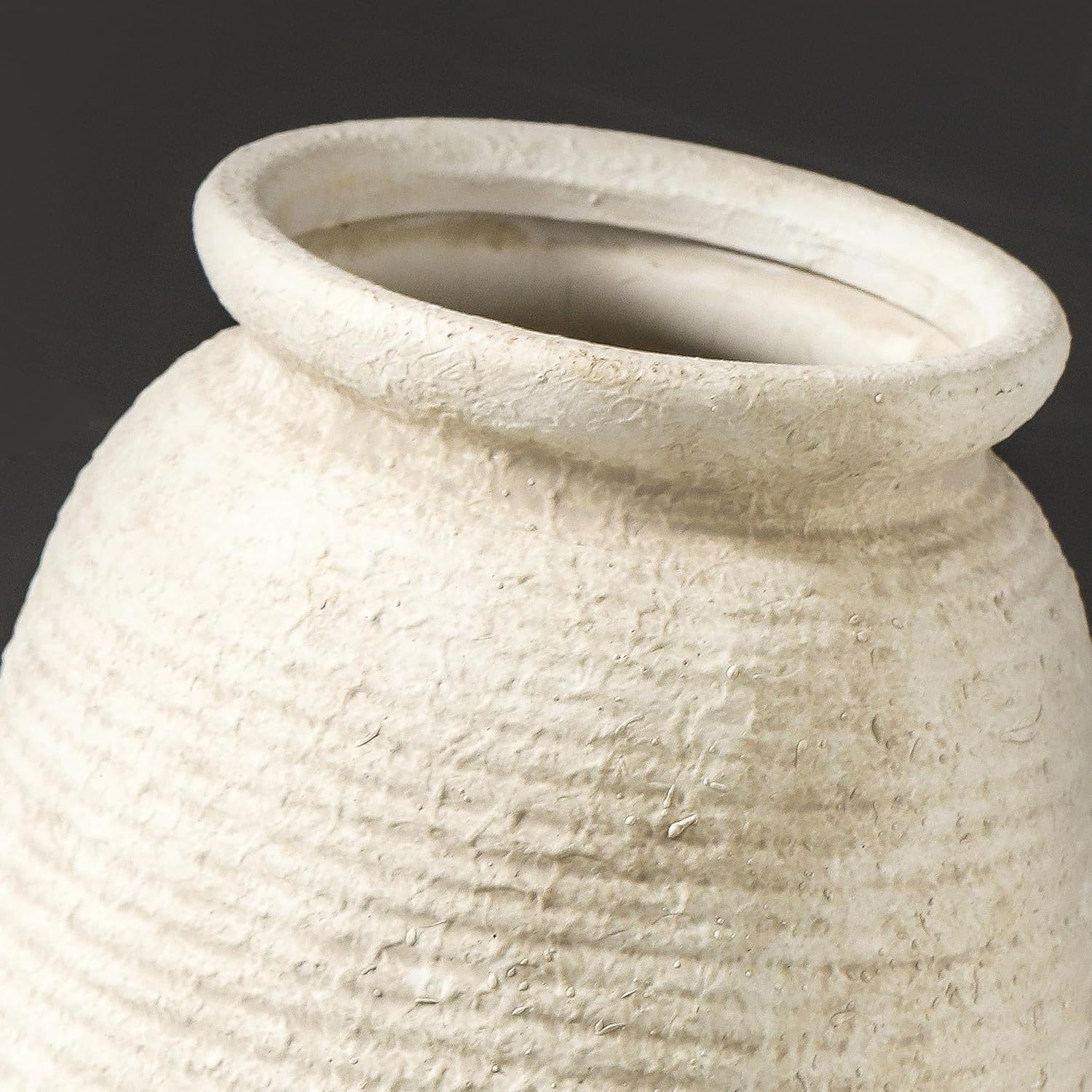 Close-up of a textured beige ceramic vase on a dark background
