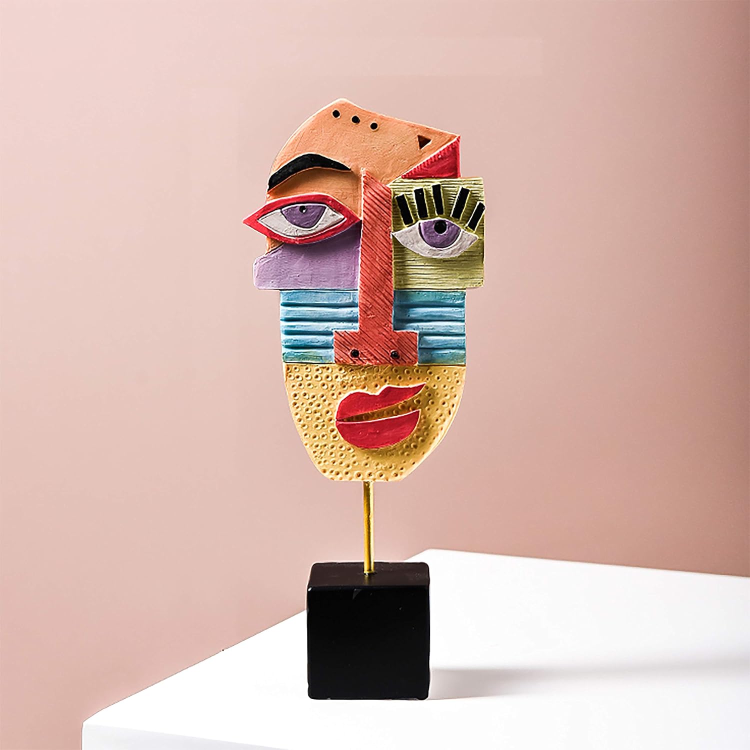 Colorful abstract face sculpture on a stand against a pink background