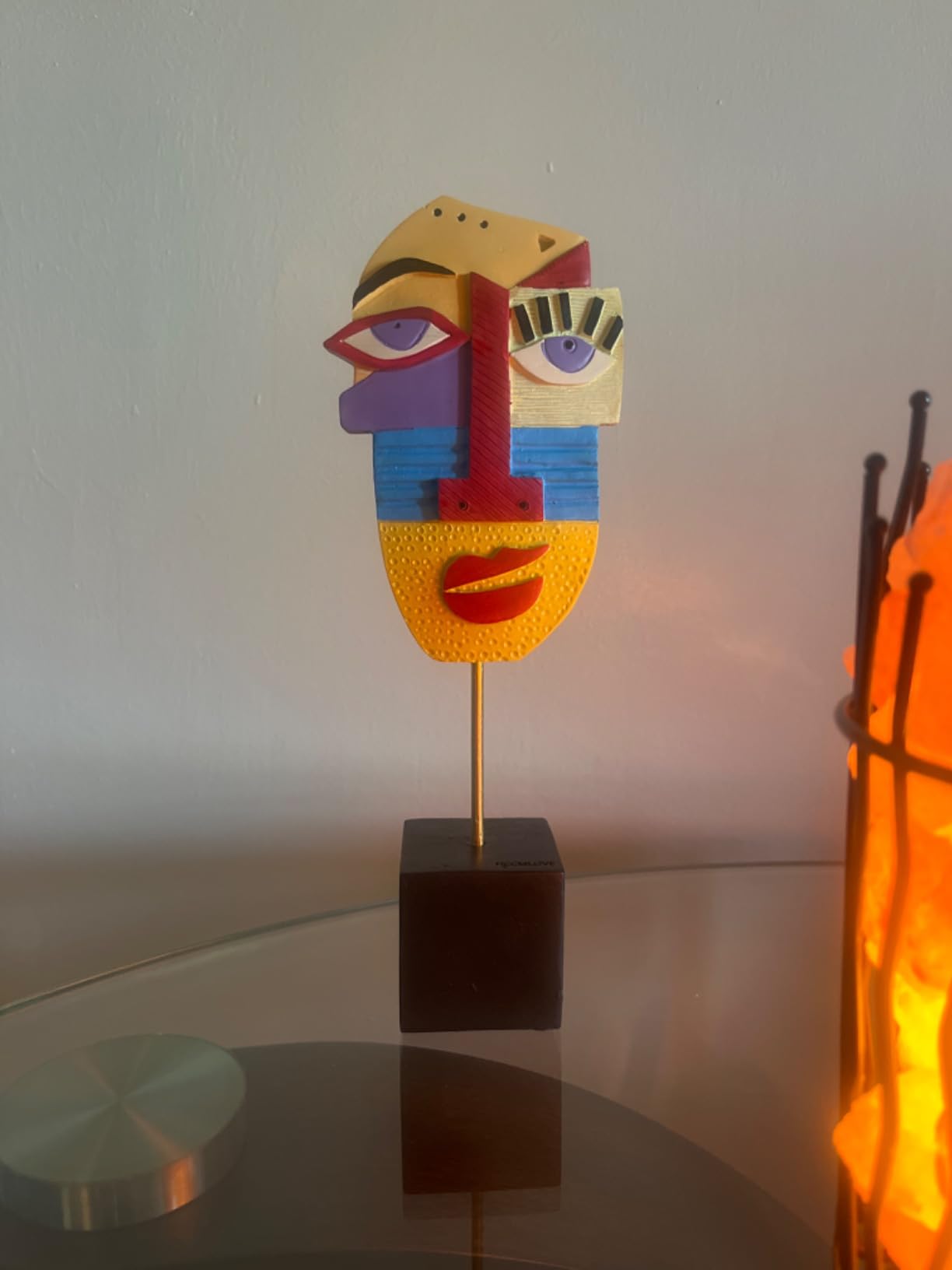 Colorful abstract face sculpture on a stand with a blurred background