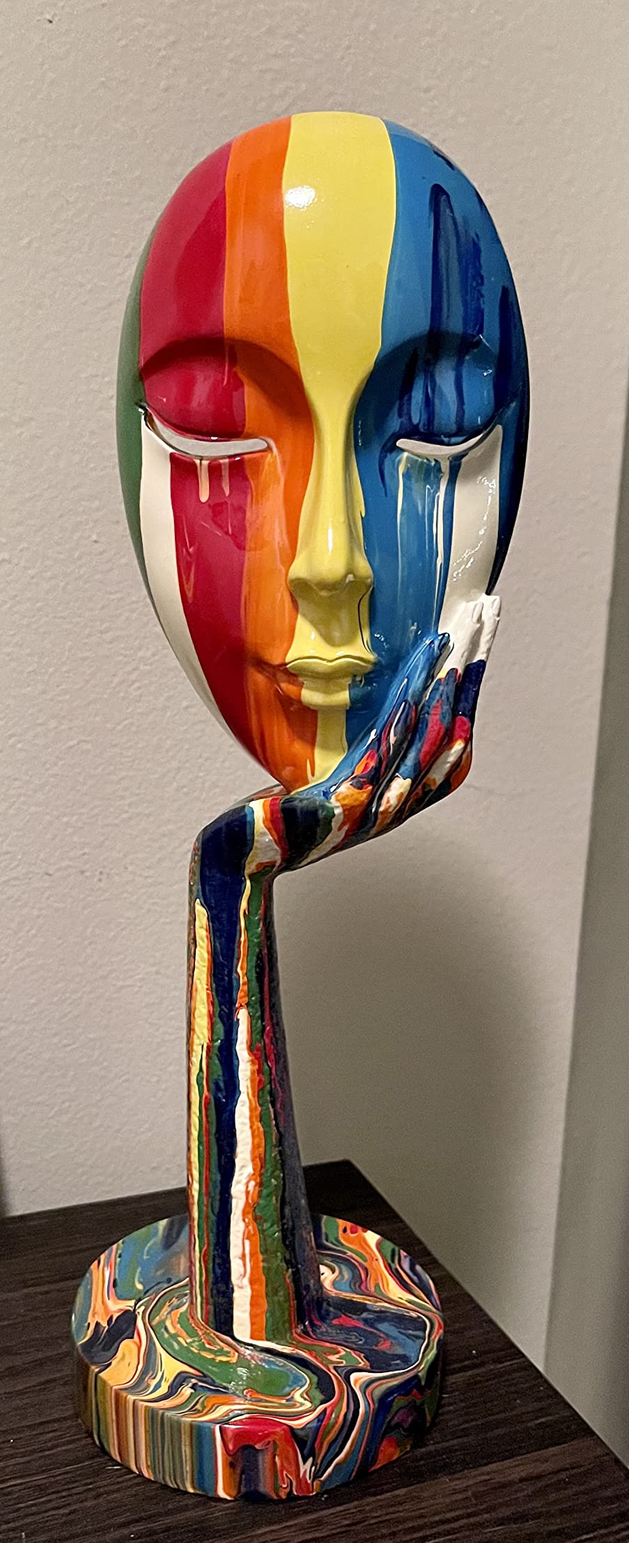 Colorful abstract sculpture of a face on a wooden surface with a plain background