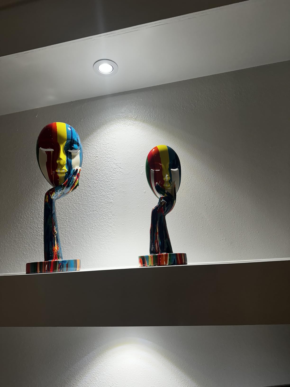 Colorful abstract sculptures on a white wall with a spotlight