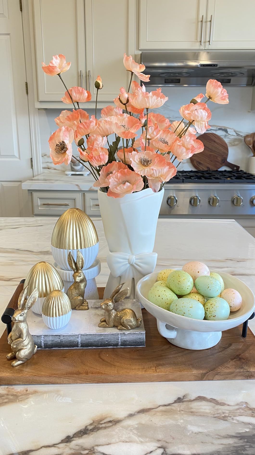 Decorative Easter setup with flowers, eggs, and figurines on a kitchen counter.