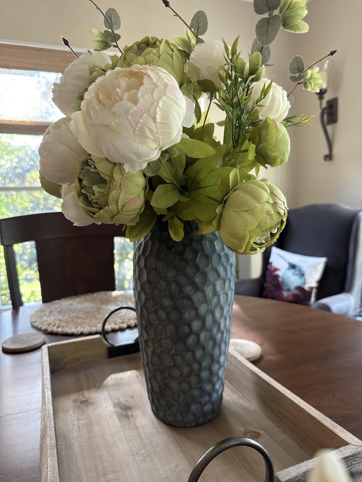 Decorative floral arrangement in a textured vase on a wooden table.