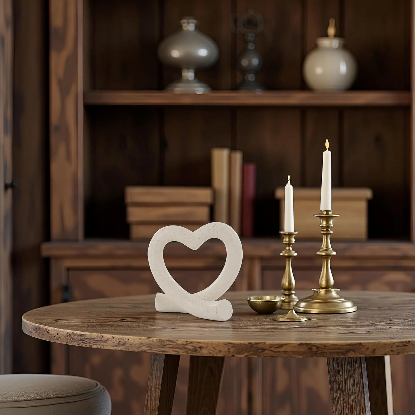 Decorative heart sculpture, candles, and small bowl on a wooden table with a blurred background