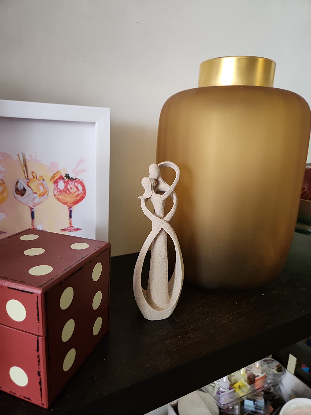 Decorative items including a large gold vase, small white sculpture, and red box with white dots on a dark surface.