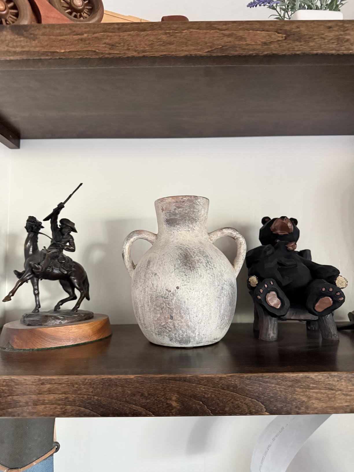 Decorative items including a statue, vase, and bear figure on a wooden shelf.