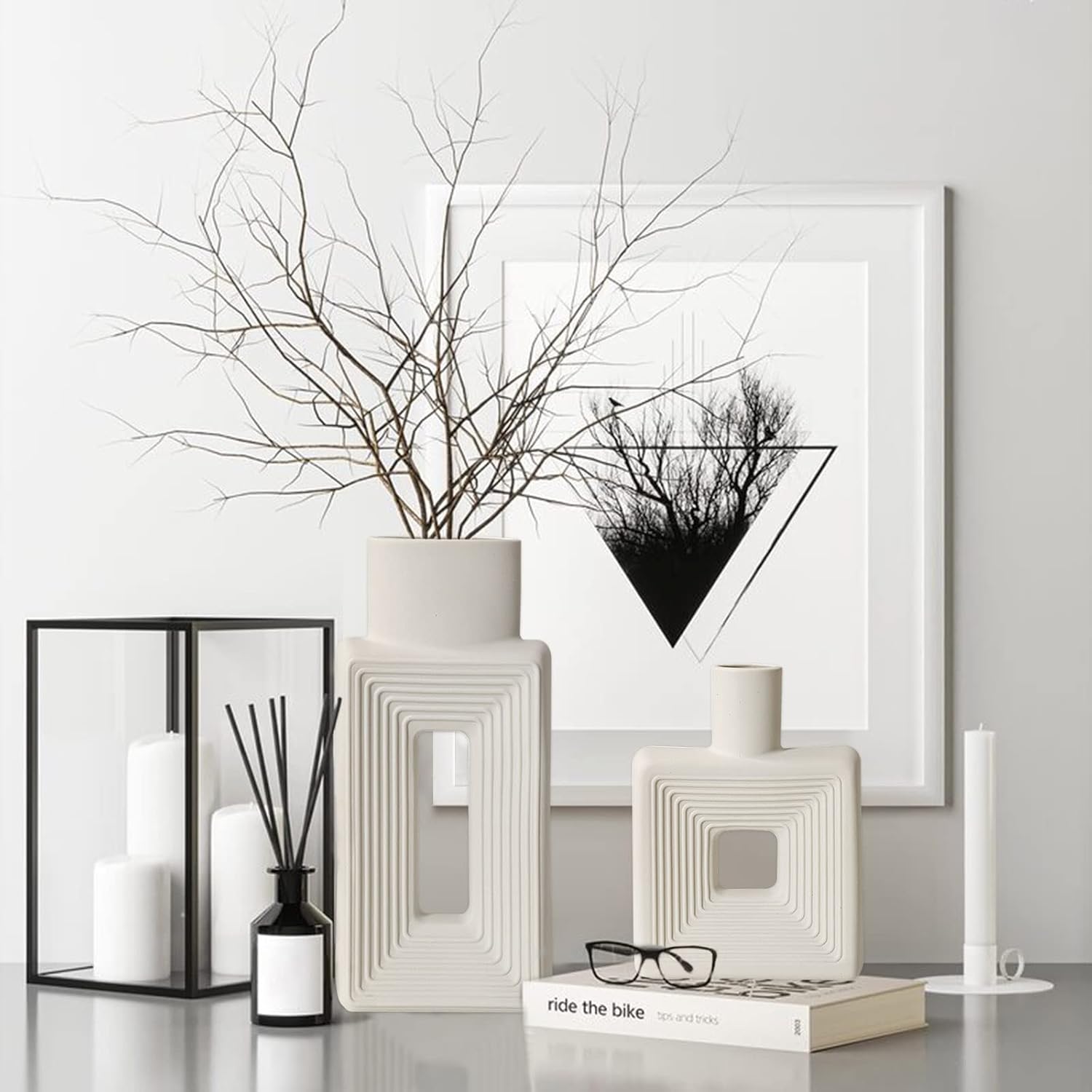 Decorative items including vases, candles, and a framed artwork on a white surface.