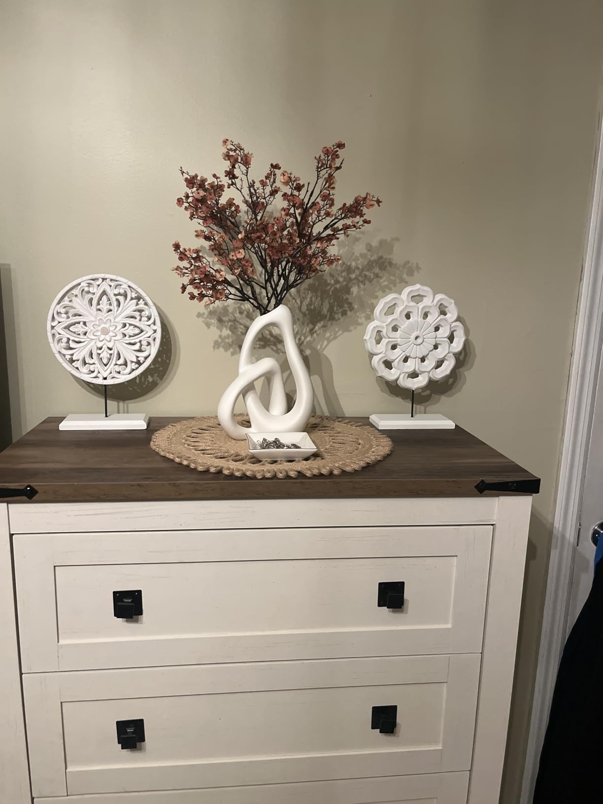 Decorative items on a wooden dresser against a beige wall