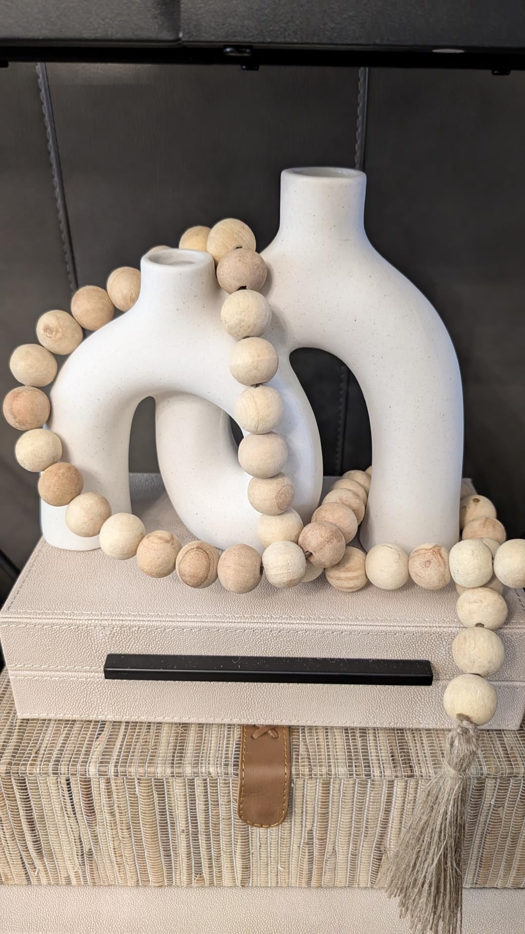 Decorative setup with white vases and wooden beads on a surface.