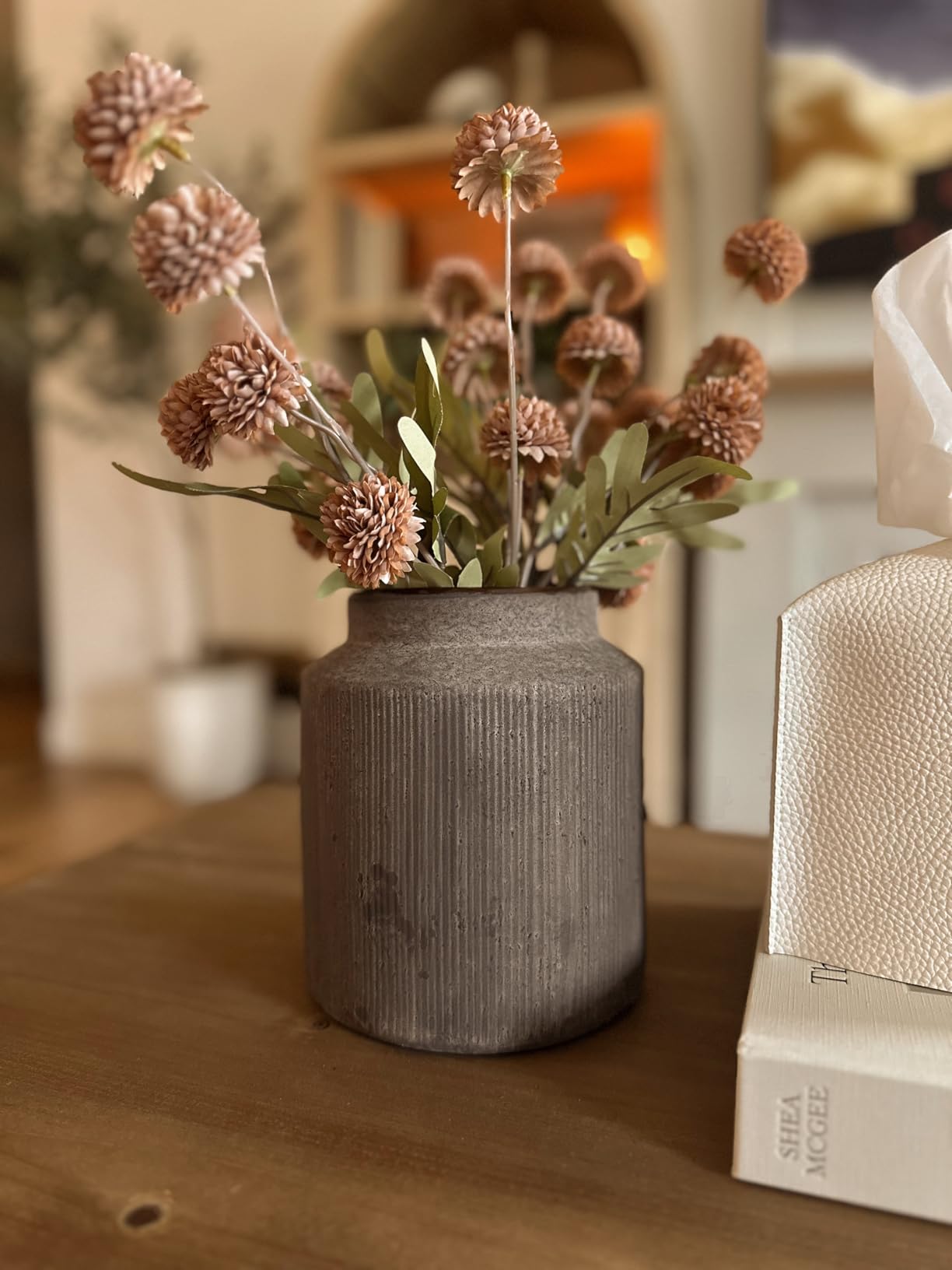 Decorative vase with dried flowers on a wooden surface in a softly blurred indoor setting