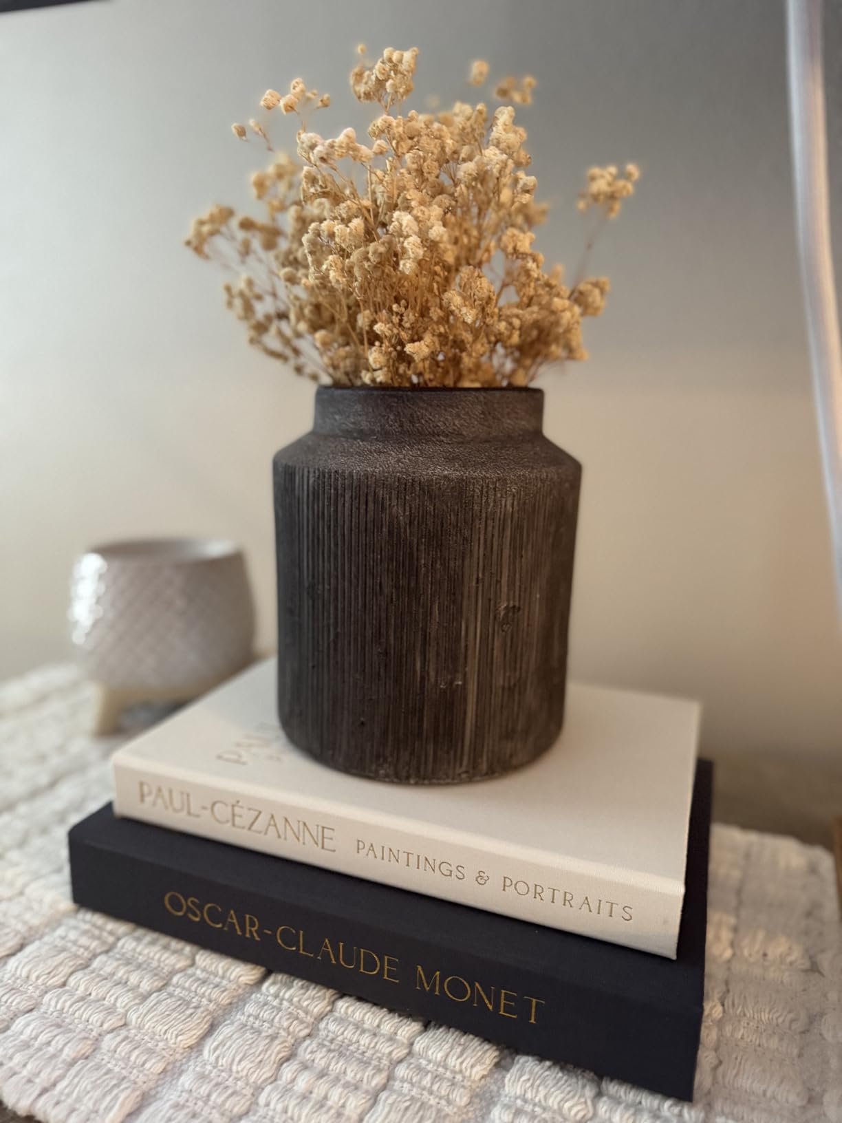 Decorative vase with dried flowers on top of books