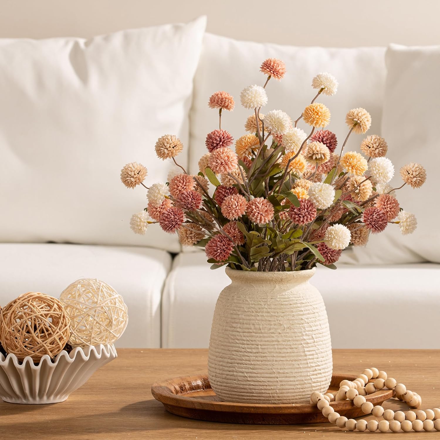Decorative vase with flowers on a table in front of a white sofa