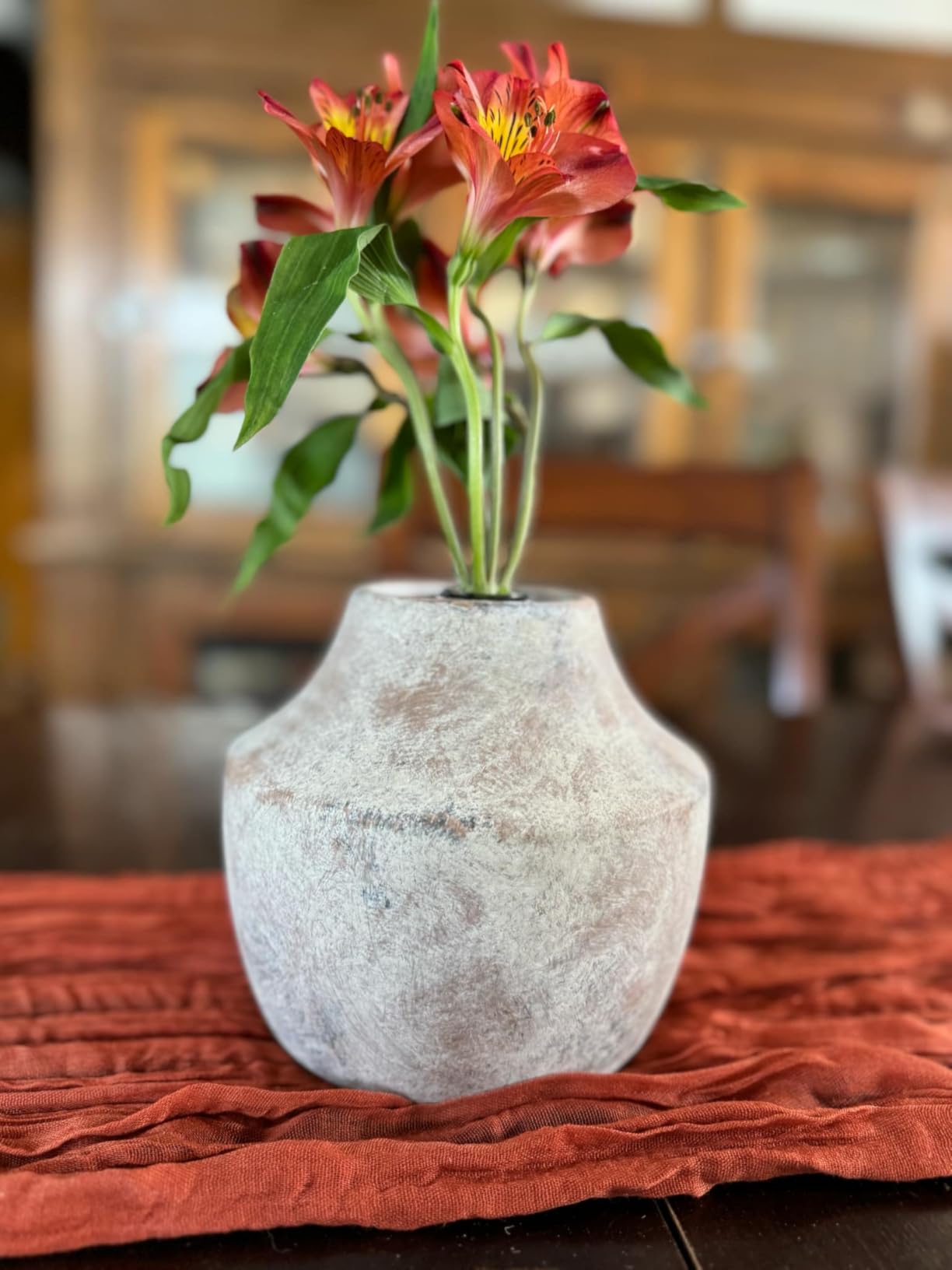 Decorative vase with flowers on a tablecloth in a blurred indoor setting