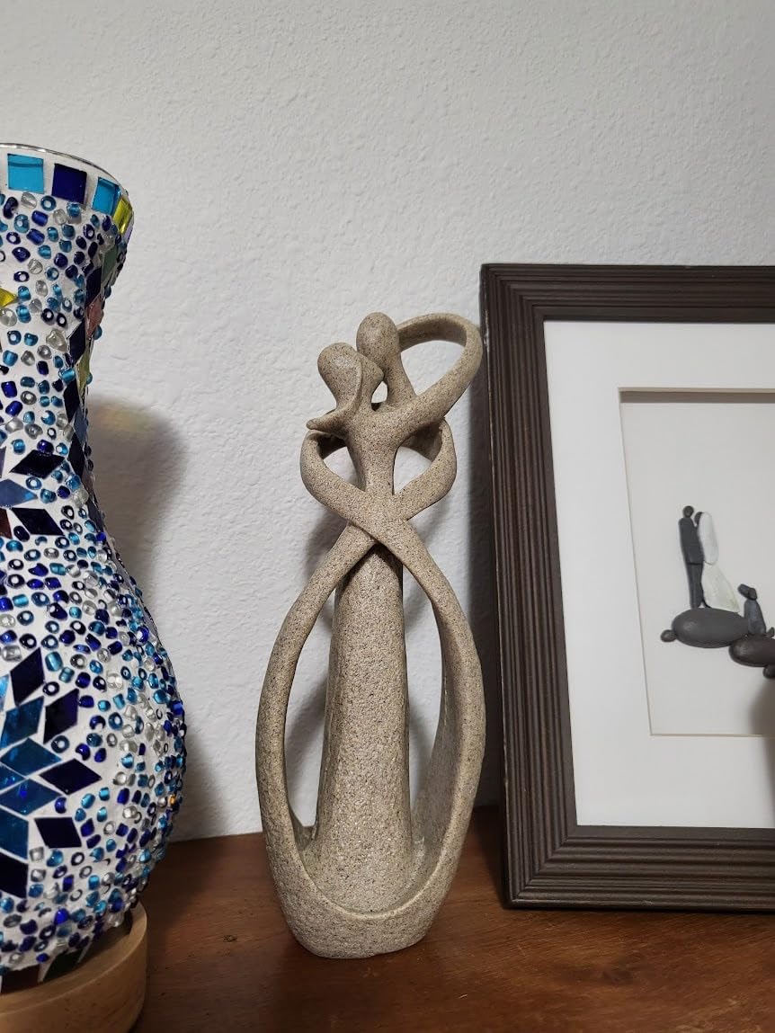 Decorative vase with geometric pattern, abstract sculpture, and framed artwork on a wooden surface.