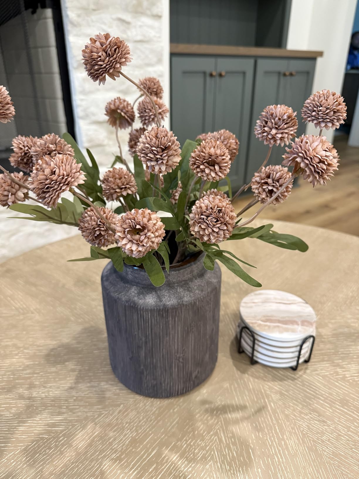 Decorative vase with pink flowers on a wooden table in a kitchen setting