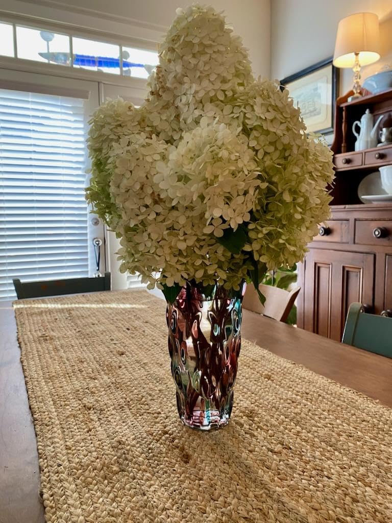 Decorative vase with white flowers on a table in a room with furniture and decor.