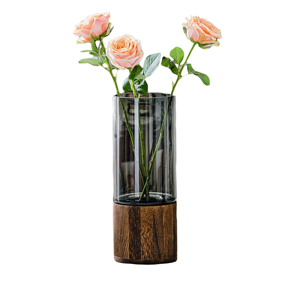 Glass vase with wooden base holding pink roses on a white background