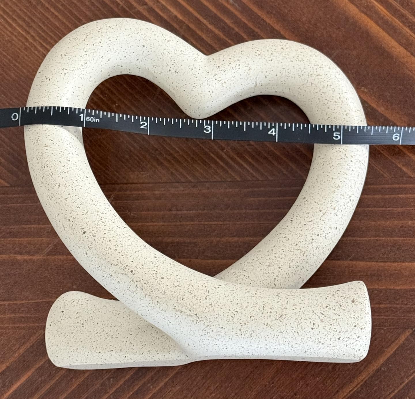 Heart-shaped stone object with a measuring tape on a wooden surface
