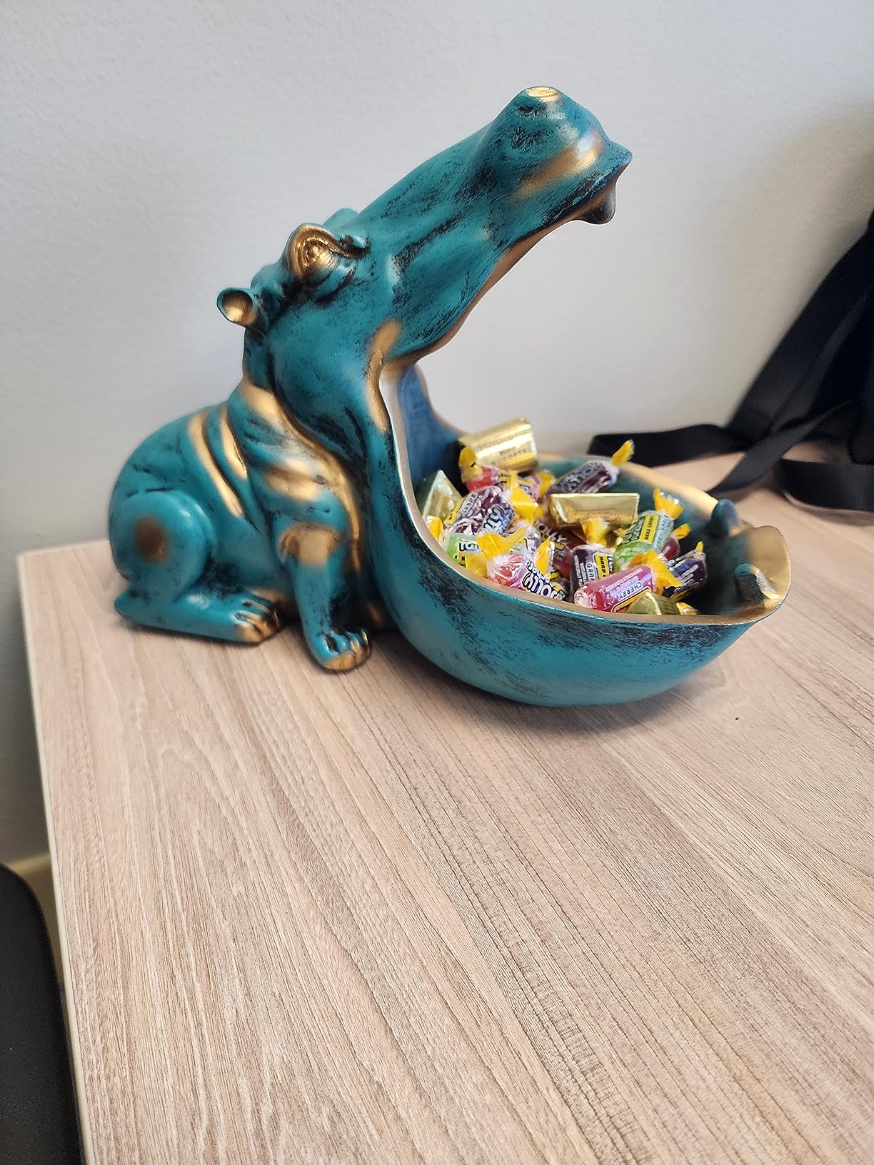 Hippo-shaped candy dish with gold accents on a wooden surface