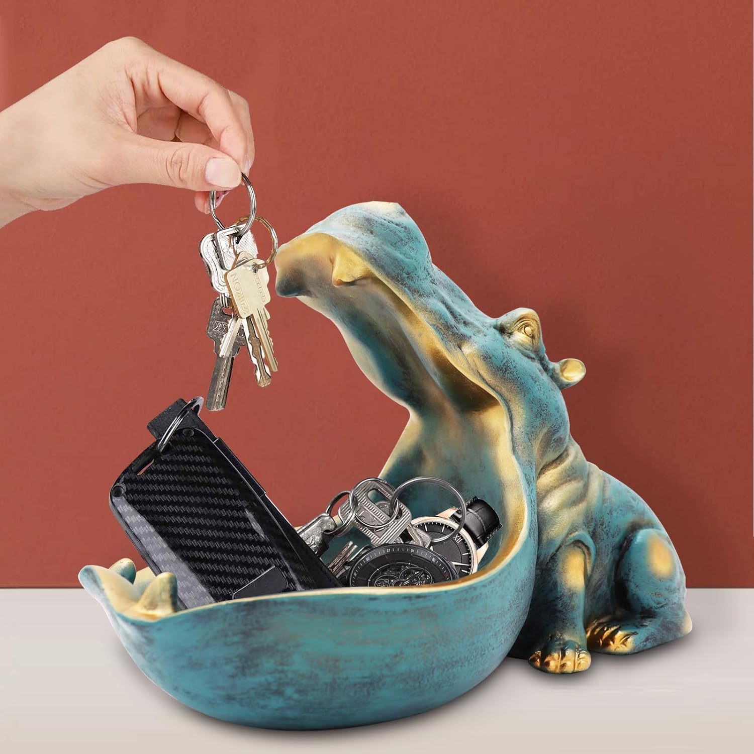 Hippo-shaped key holder with keys and phone on a red background