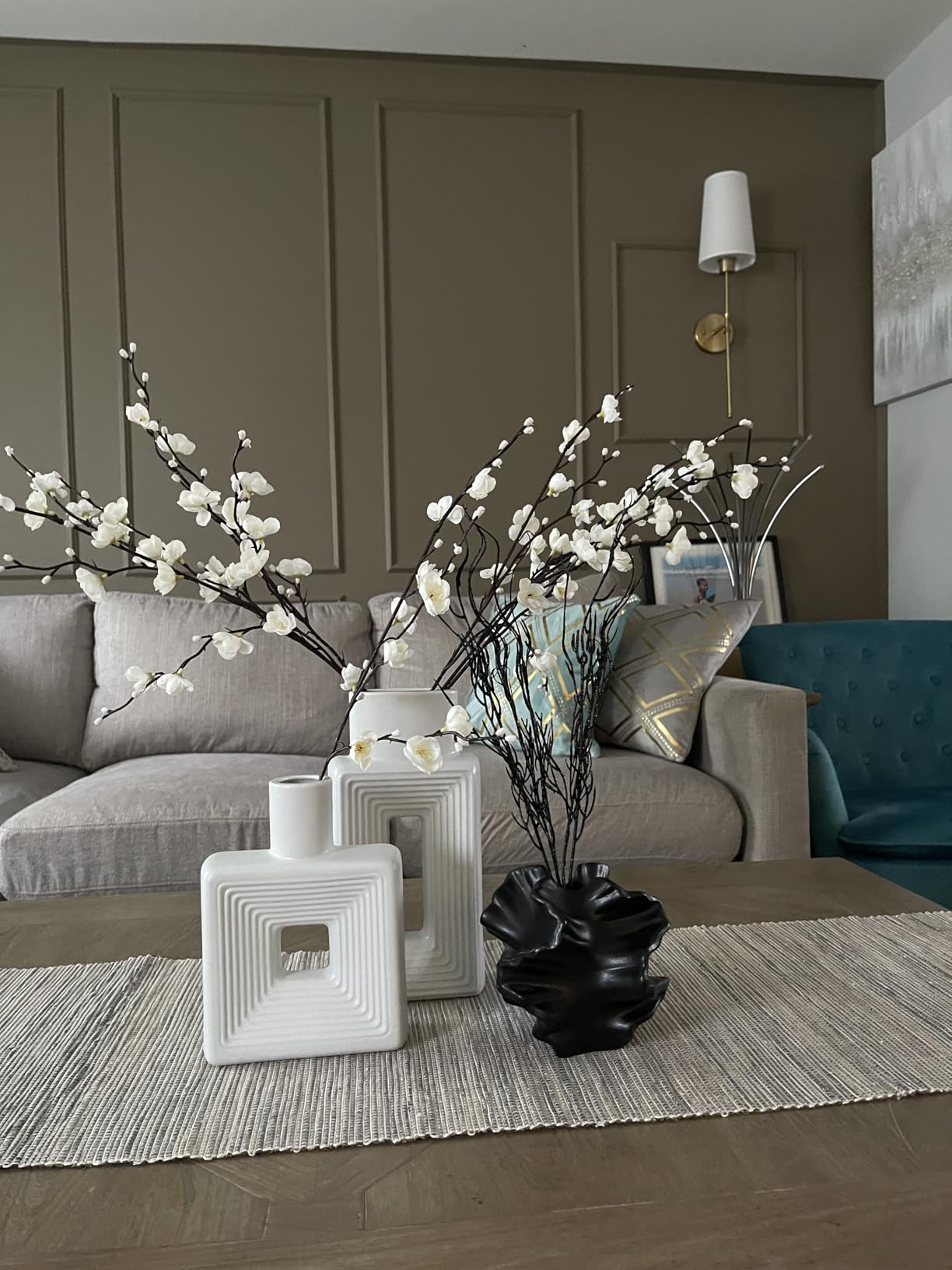 Living room with gray sofa, decorative plants, and vases on a wooden table.