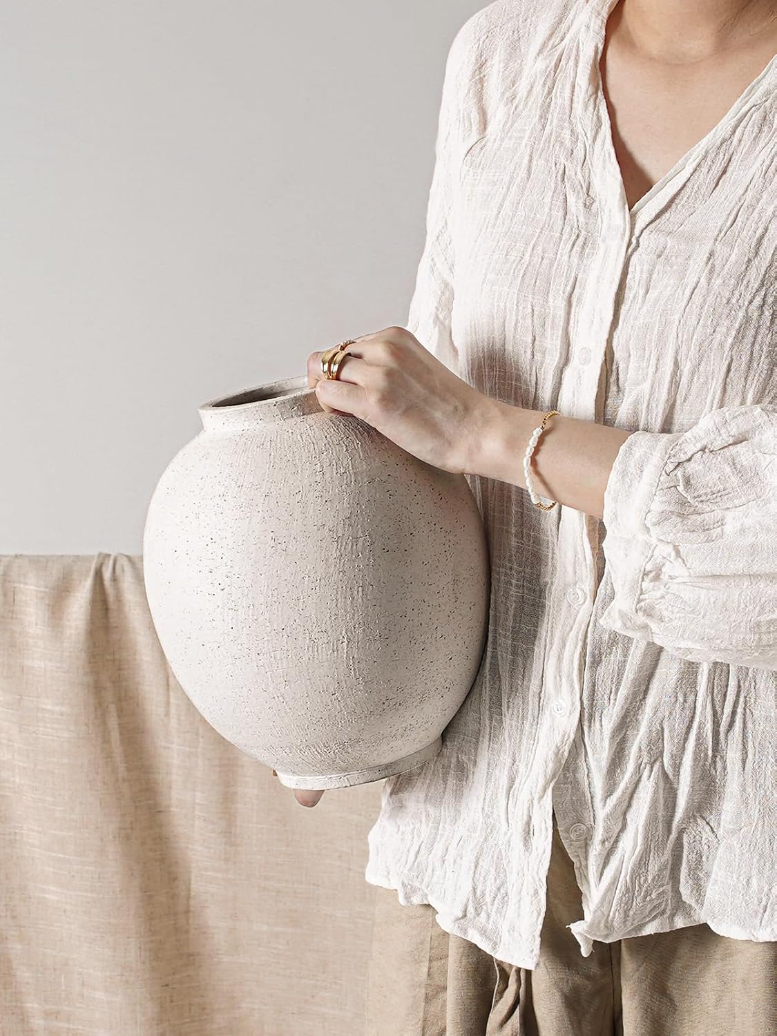 Person holding a large ceramic vase against a neutral background