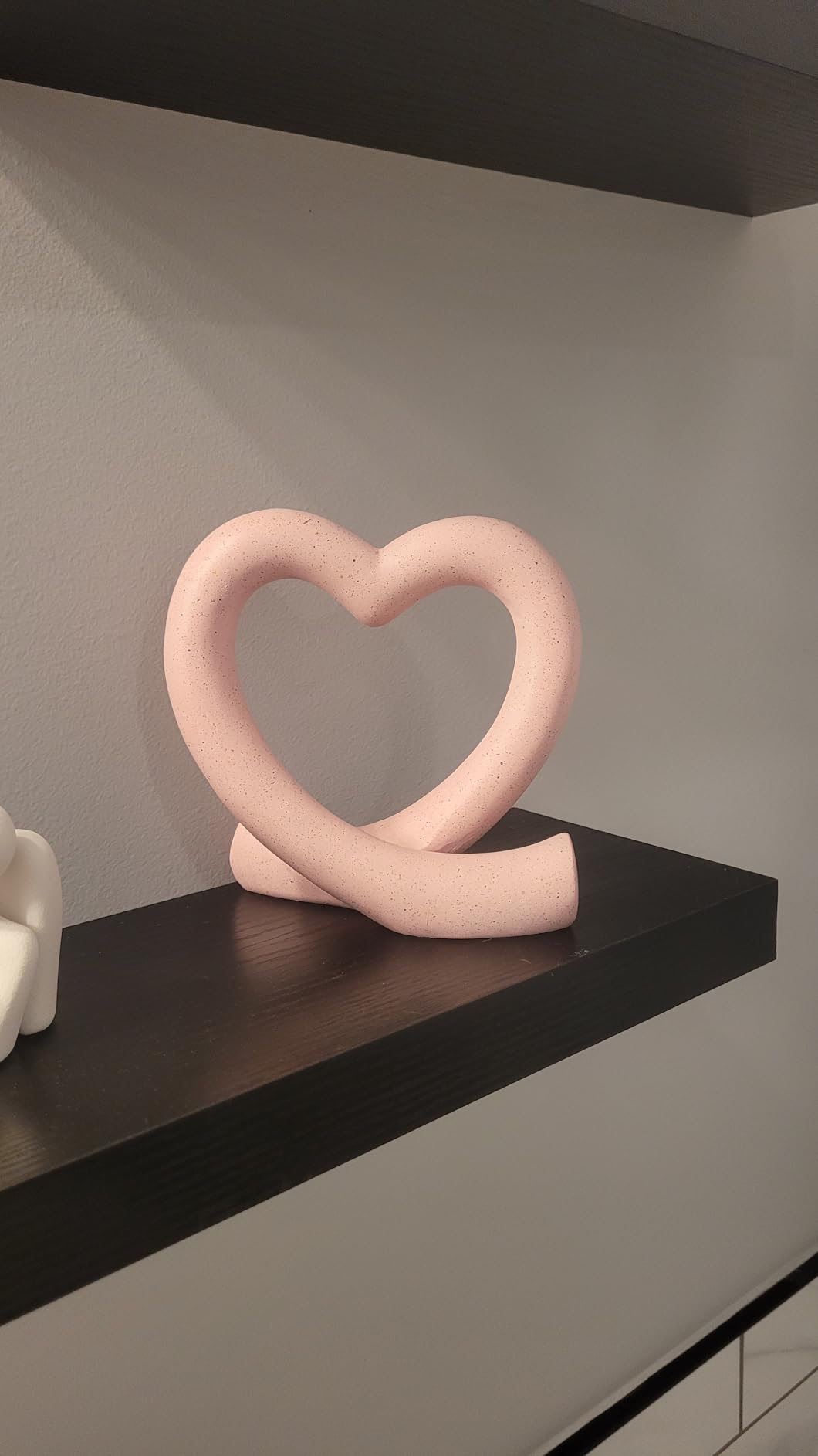 Pink heart-shaped sculpture on a dark surface with a neutral background