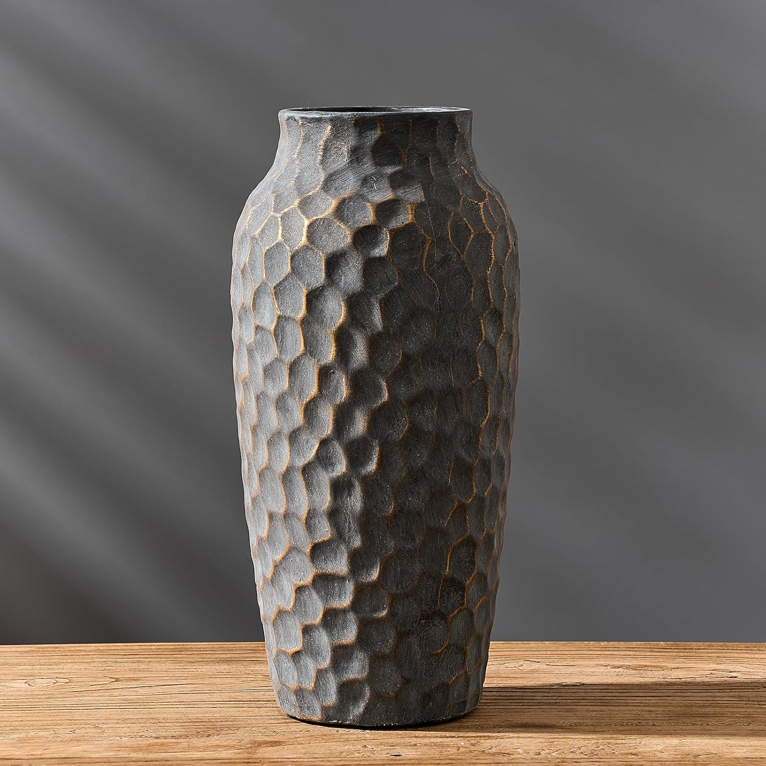 Textured vase on a wooden surface with a gray background