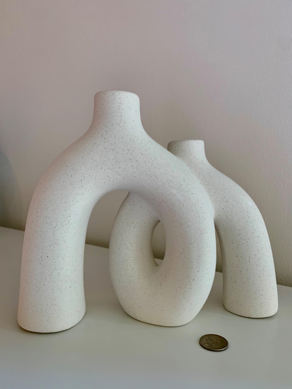 Three white ceramic vases of different shapes on a light surface with a plain background