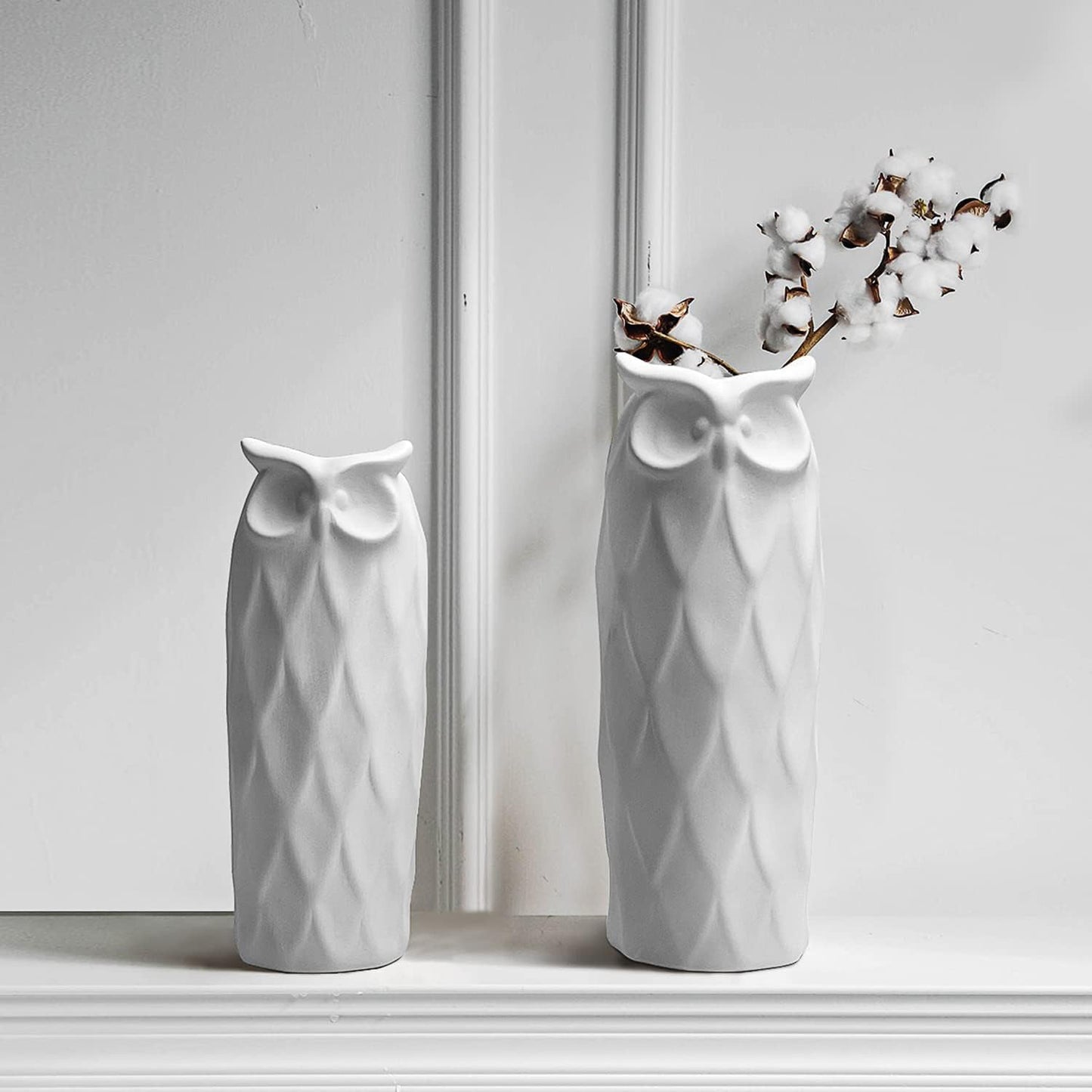 Two white owl-shaped vases on a light surface with a neutral background