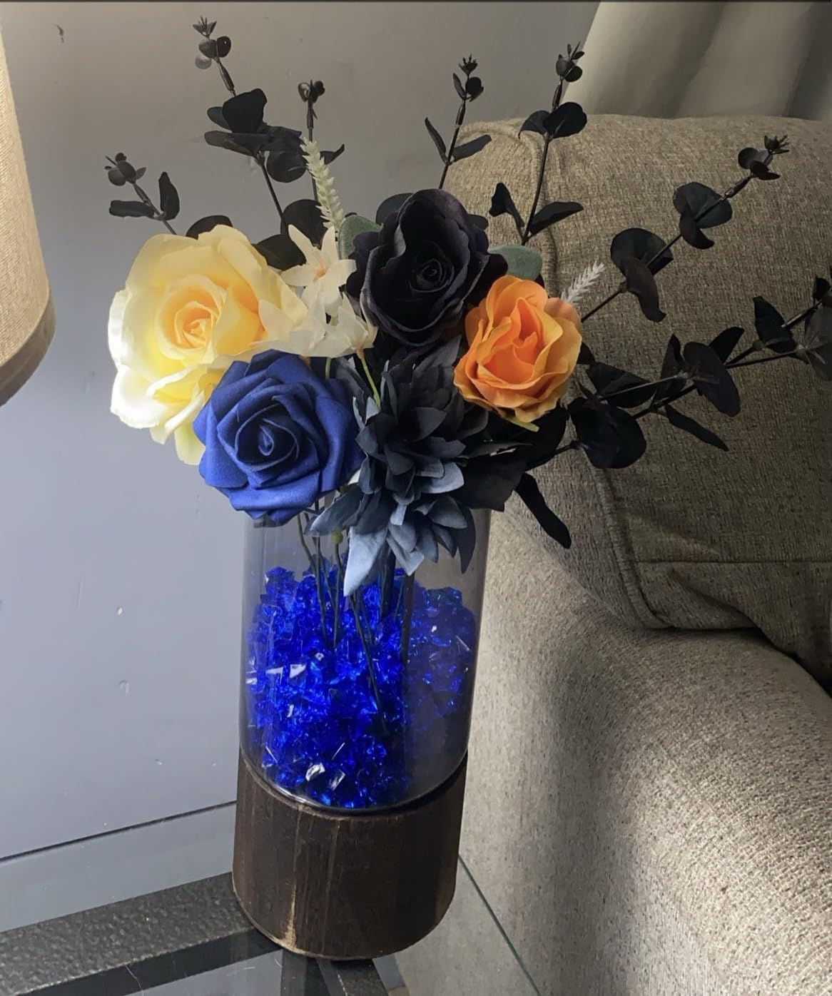 Vase with colorful flowers and blue beads on a surface