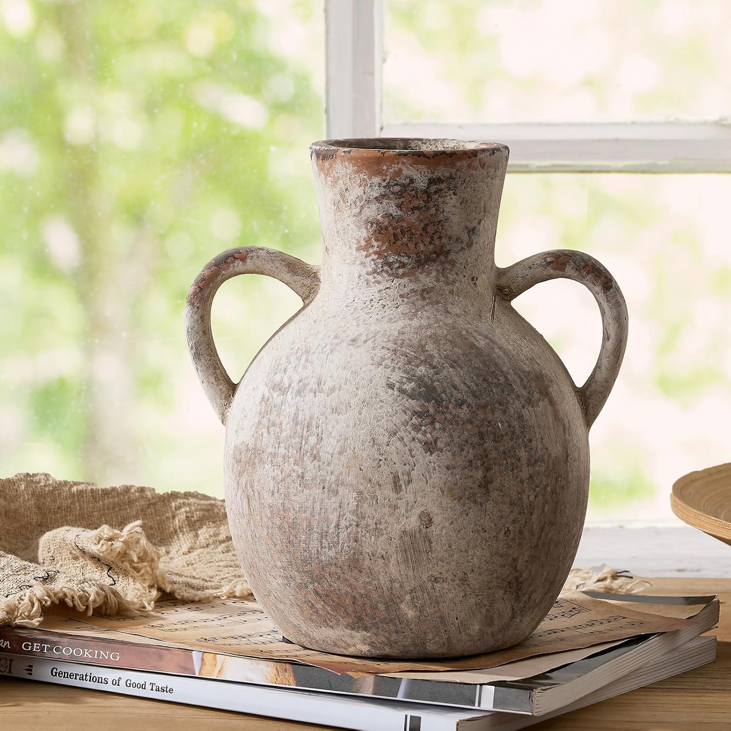 Vintage-style terracotta vase on a stack of books with a blurred natural background