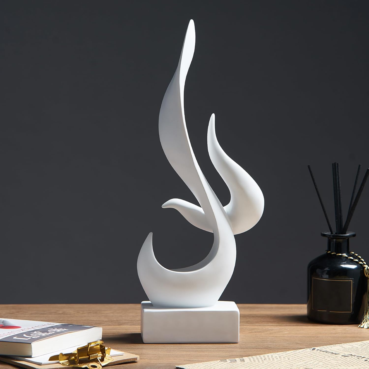 White abstract sculpture on a wooden surface with a dark background
