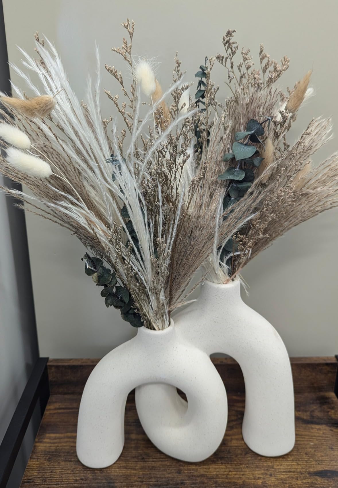 White abstract vase with dried plants on a wooden surface