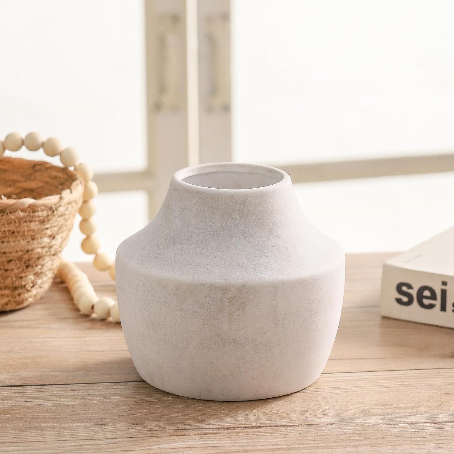 White ceramic vase on a wooden surface with a blurred background