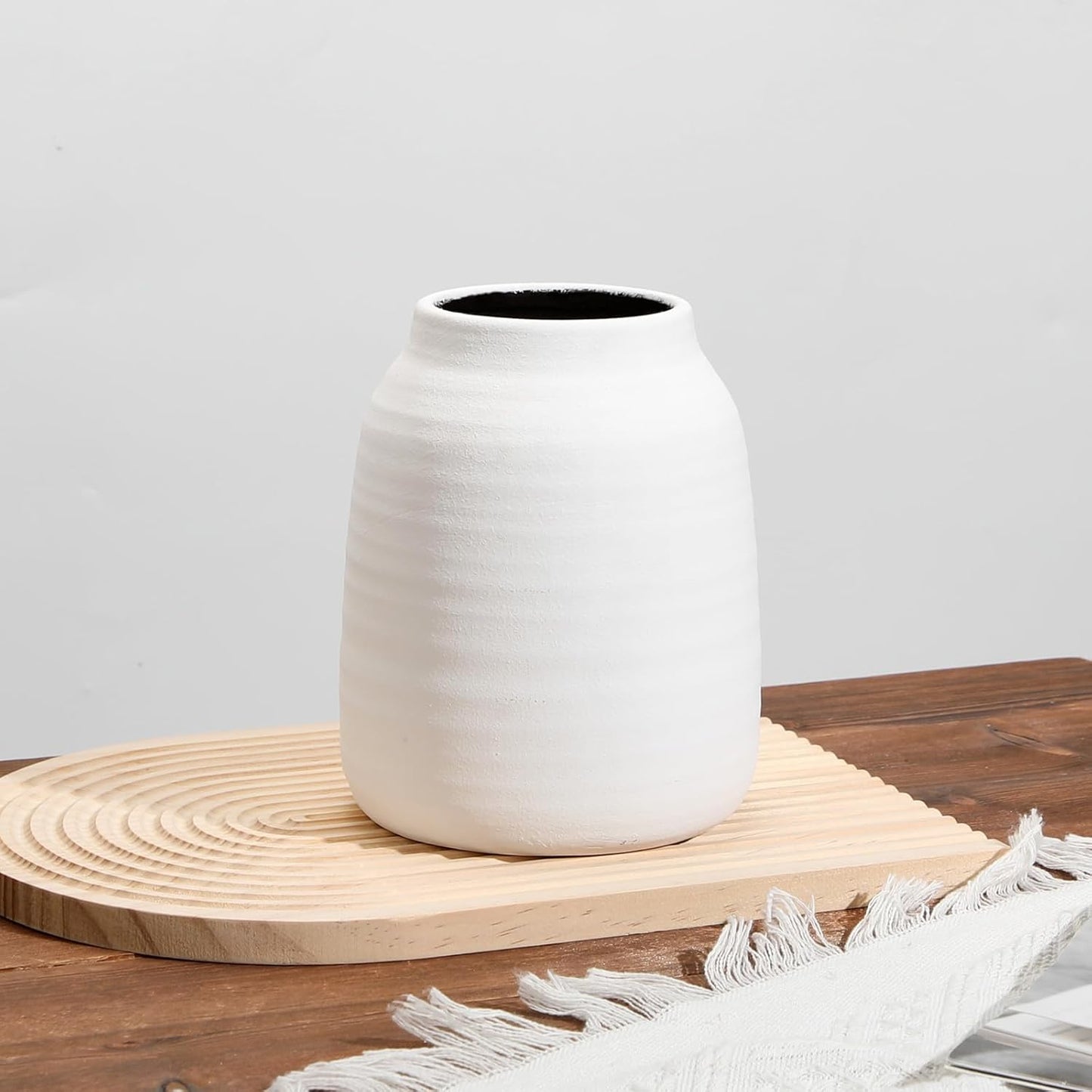 White ceramic vase on a wooden surface with a white background