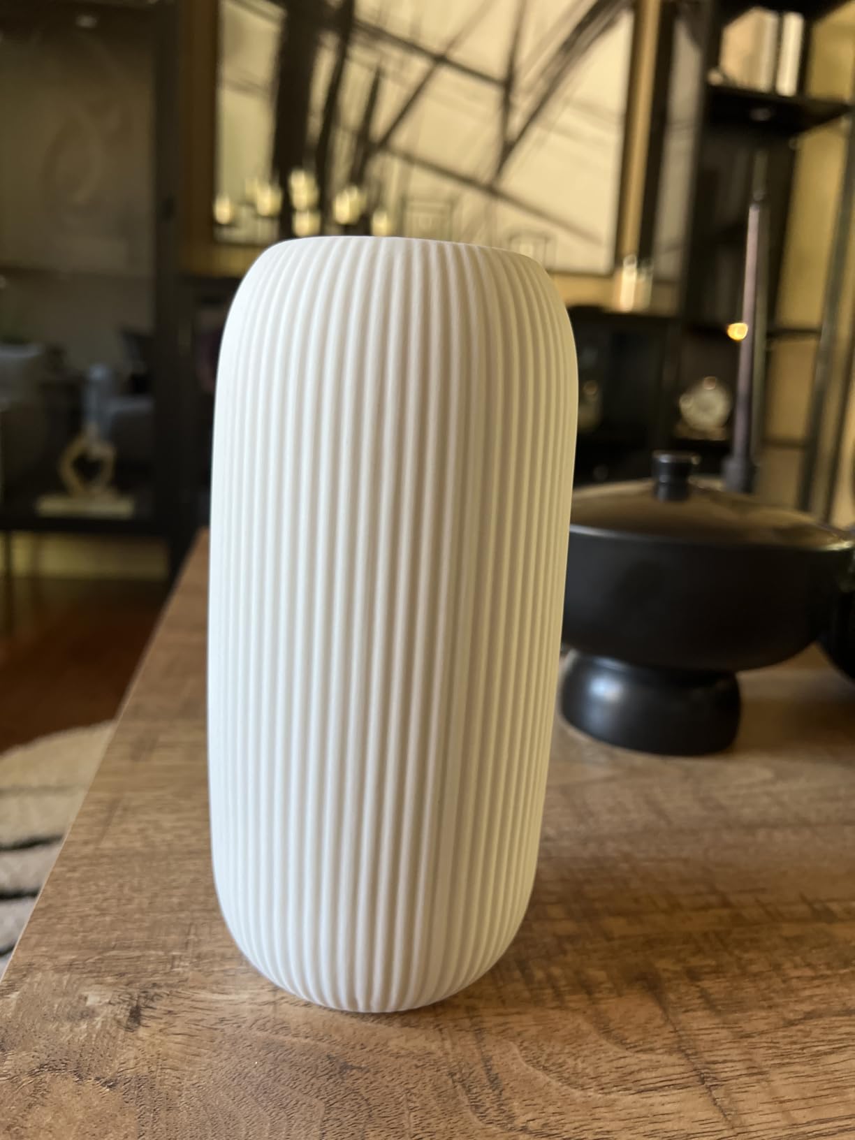 White ribbed vase on a wooden surface with a blurred background