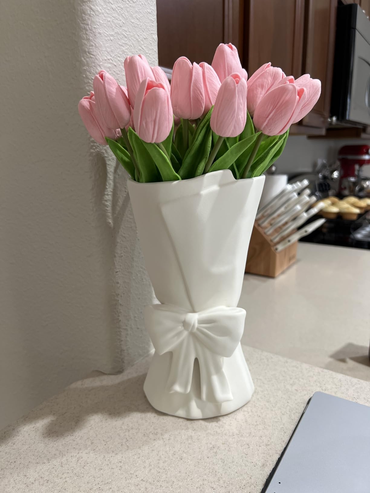 White vase with pink tulips on a kitchen counter